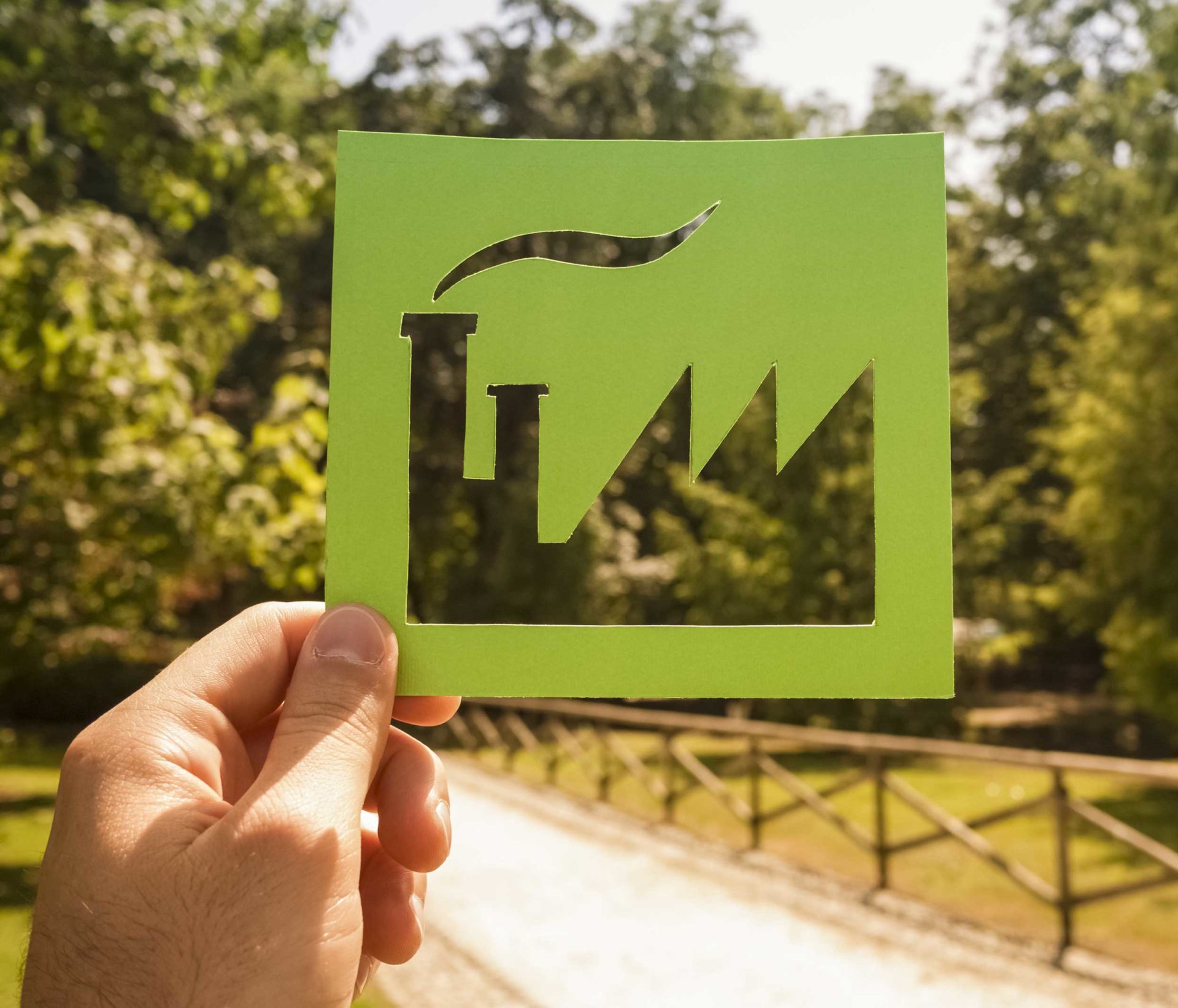 Hand met uit karton geknipte fabriek