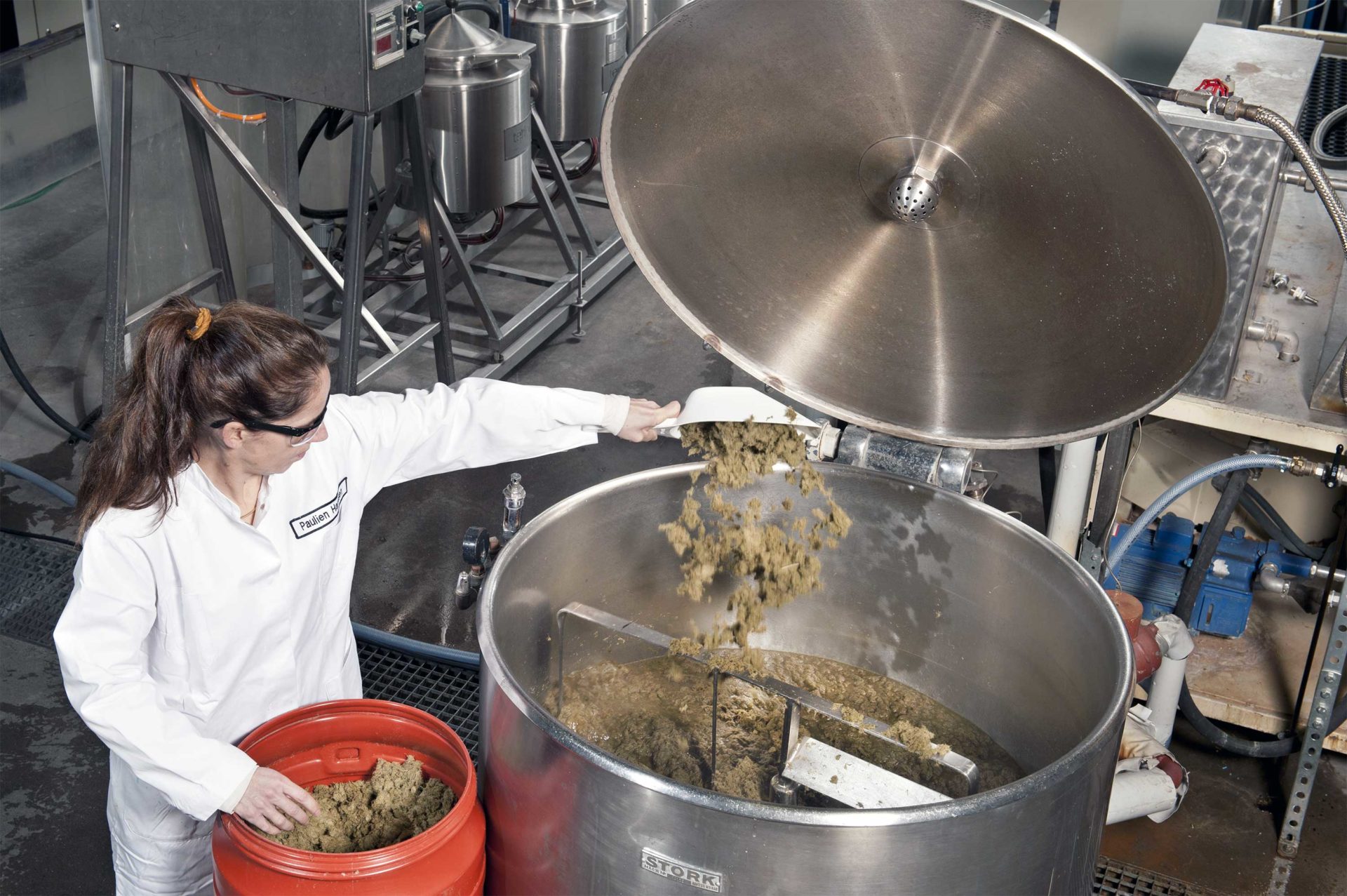 Vrouw gooit biomassa in reactorvat