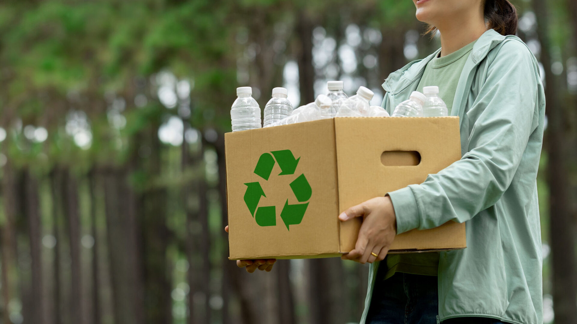 Vrouw met doos vol flessen, recyclinglogo